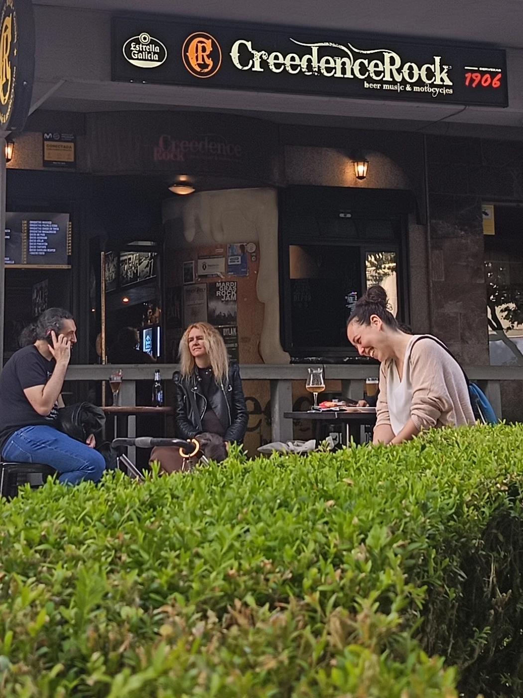 Fachada del Creedence Rock Bar en A Coruña, con el rótulo del local y clientes en la terraza